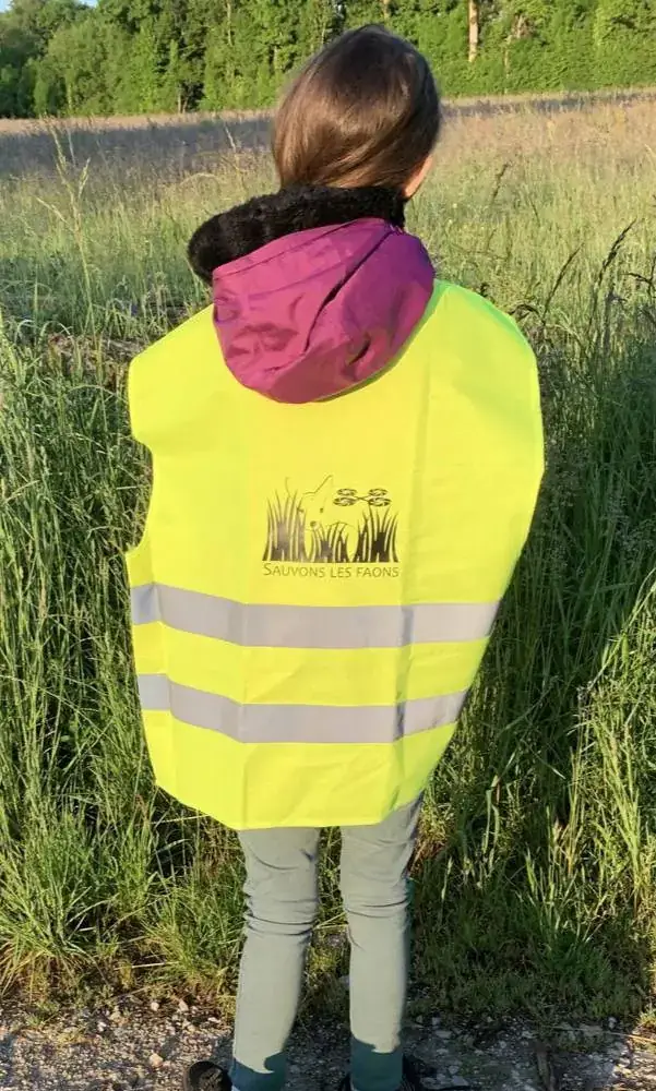 Bénévole de l'association, gilet « Sauvons les Faons » sur le dos, en bordure de prairie